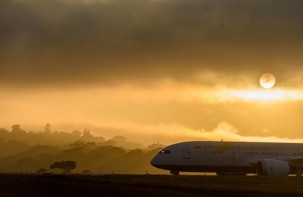 Royal Brunei taxiing on Melbourne Airport runway at sunset