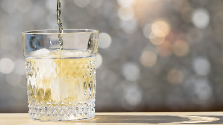 A whisky cocktail is poured into a glass