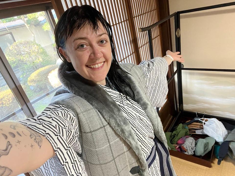 Author Emily Pennington smiling in Japan next to suitcase