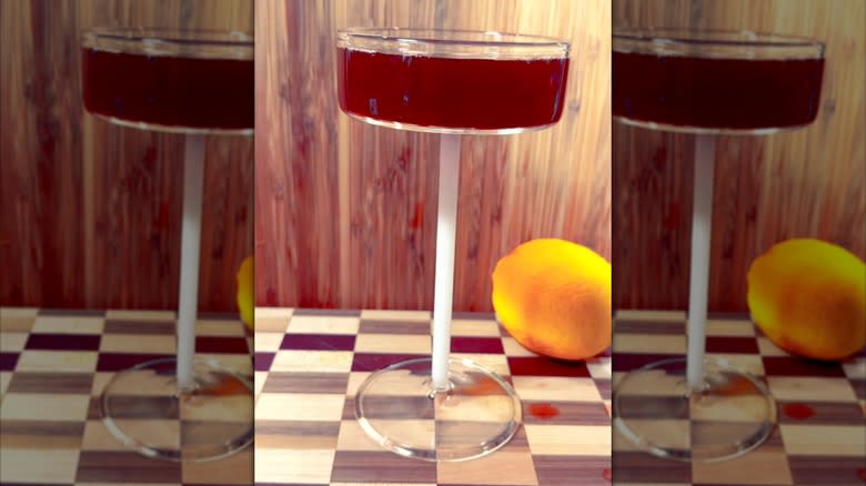 A black ship cocktail sits next to a lemon