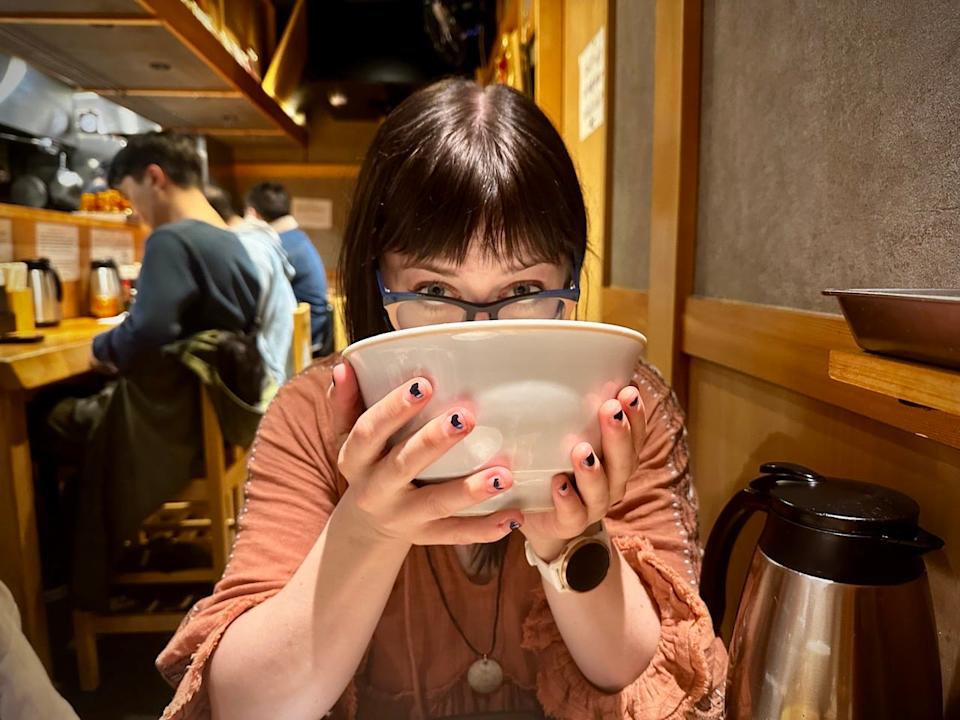 Author Emily Pennington with bowl tilted into mouth in JApan 