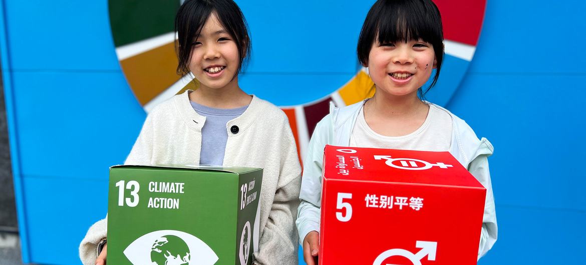 Kaneko Sayaka (left) and her sister hold up displays promoting the SDGs.
