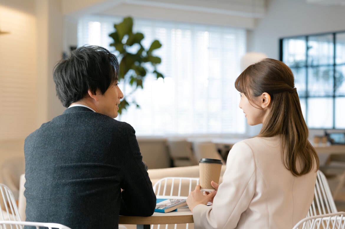 Man and a woman having a coffee date, picture taken of their backs as they look at each other