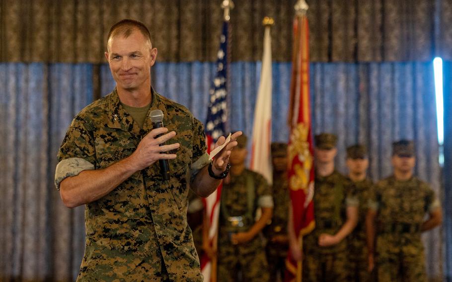 A man speaks during a ceremony in a room.