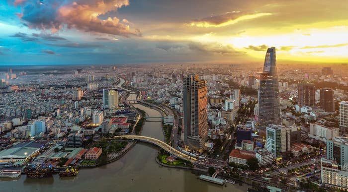 Aerial view of a bustling city with a winding river, modern skyscrapers, and a vibrant cityscape at sunset