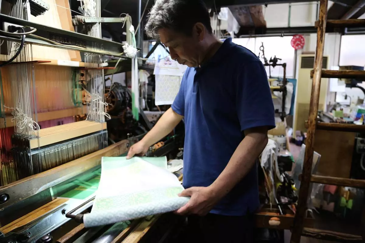 Hironori Fukuoka, the fourth-generation successor to his Nishijinori business, looks at the fabric that is a collaboration with AI in Kyoto, western Japan on July 3, 2025. (AP Photo/Yuri Kageyama)