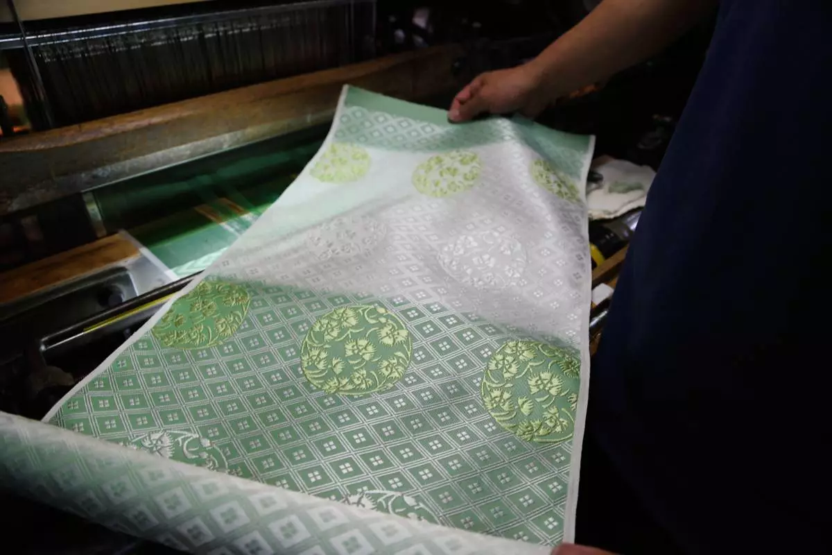 Hironori Fukuoka, the fourth-generation successor to his Nishijinori business, looks at the fabric that is a collaboration with AI in Kyoto, western Japan on July 3, 2025. (AP Photo/Yuri Kageyama)
