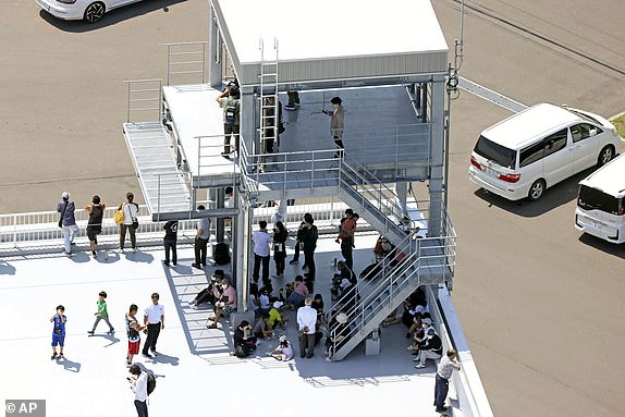 People take shelter on the roof of a fire station in Mukawa town, Hokkaido, northern Japan Wednesday, July 30, 2025, after a powerful earthquake in Russia's Far East prompted tsunami alert in parts of Japan. (Kyodo News via AP)