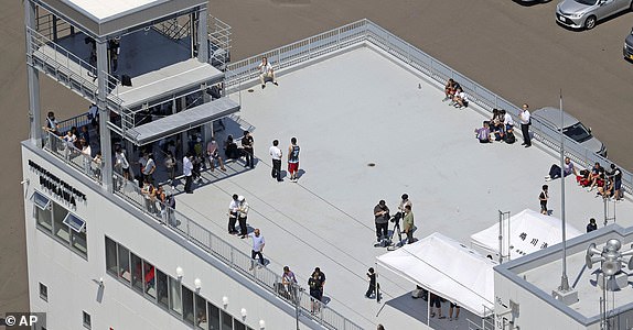 People take shelter on the roof of a fire station in Mukawa town, Hokkaido, northern Japan Wednesday, July 30, 2025, after a powerful earthquake in Russia's Far East prompted tsunami alert in parts of Japan. (Kyodo News via AP)