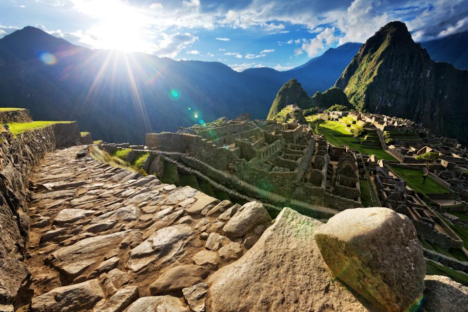 Sunrise over ancient Incan ruins of Machu Picchu, with terraced stone structures surrounded by lush mountains