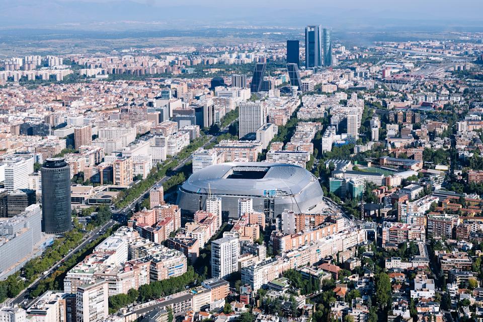 Aerial view of Madrid, showcasing the Santiago Bernabéu Stadium surrounded by urban architecture and skyline