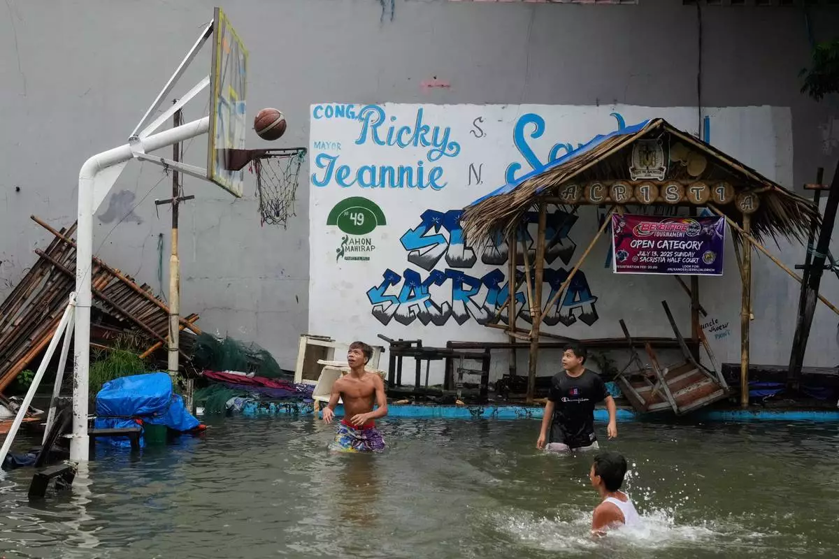 Boys play basketball at a flooded court as Typhoon Co-may intensified seasonal monsoon rains at Malabon city, Philippines on Friday, July 25, 2025. (AP Photo/Aaron Favila)