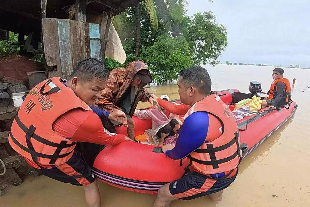 In this photo provided by the Philippine Coast Guard, rescuers assist a man to a rubber boat as they bring him to safer grounds following floods in Mamburao, Occidental Mindoro province, Philippines on Wednesday July 23, 2025. (Philippine Coast Guard via AP)3