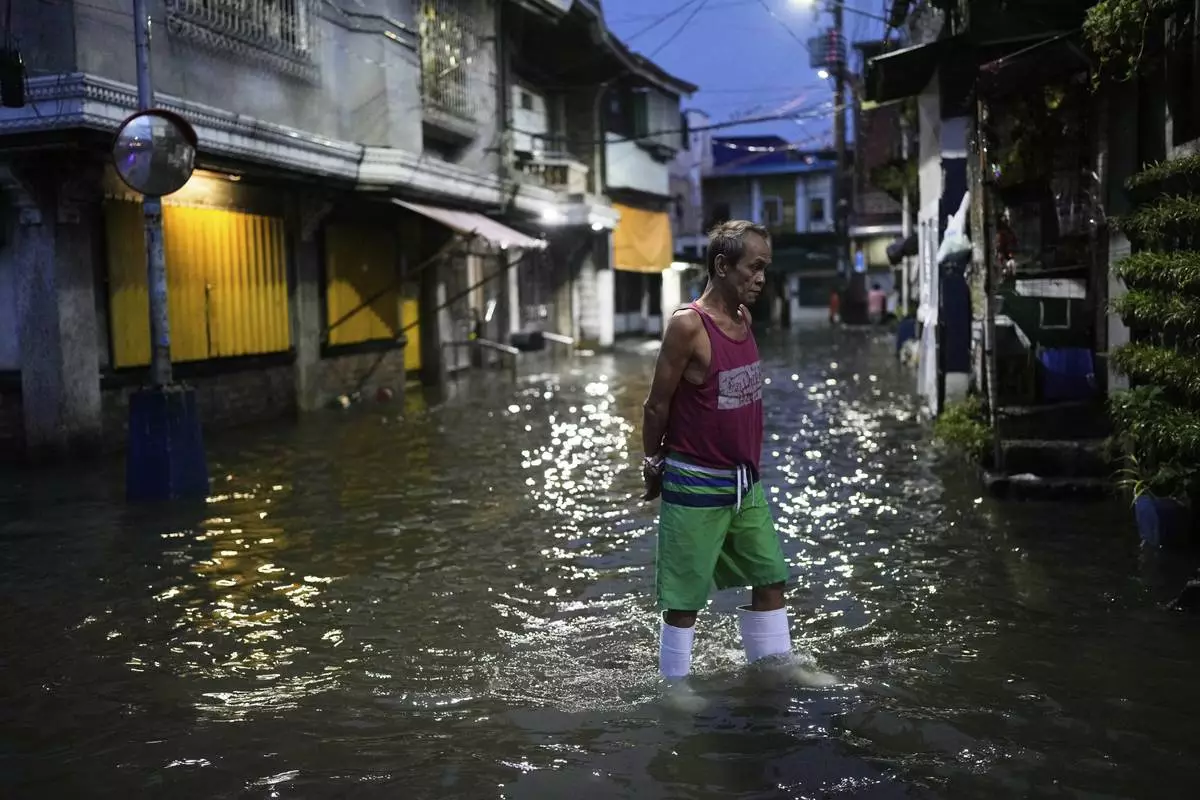 A man walks along a flooded road as intense rains continue due to the southwest monsoon at Malabon city, Philippines on Thursday, July 24, 2025. (AP Photo/Aaron Favila)