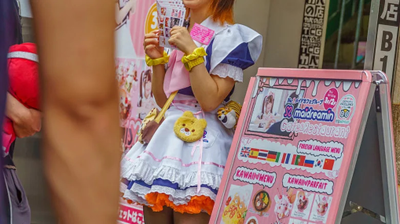 A woman in a maid costume handing out flyers for the café