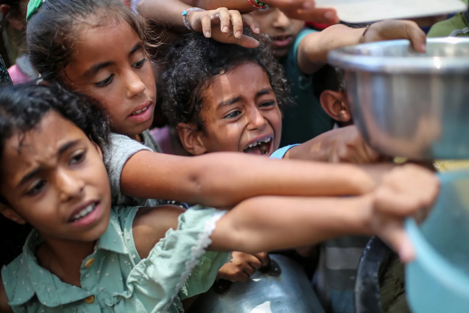 Palestinian children line up to receive a hot meal at a food distribution point in Nuseirat, Gaza, on June 30.