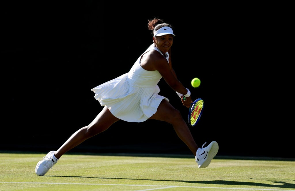 Naomi Osaka playing a backhand at Wimbledon in 2025.