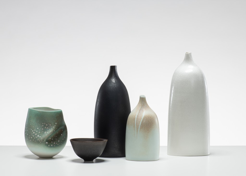 A group of handmade ceramic vessels on a white surface.