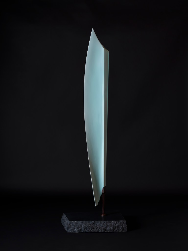 A tall blue sculpture on a black background.