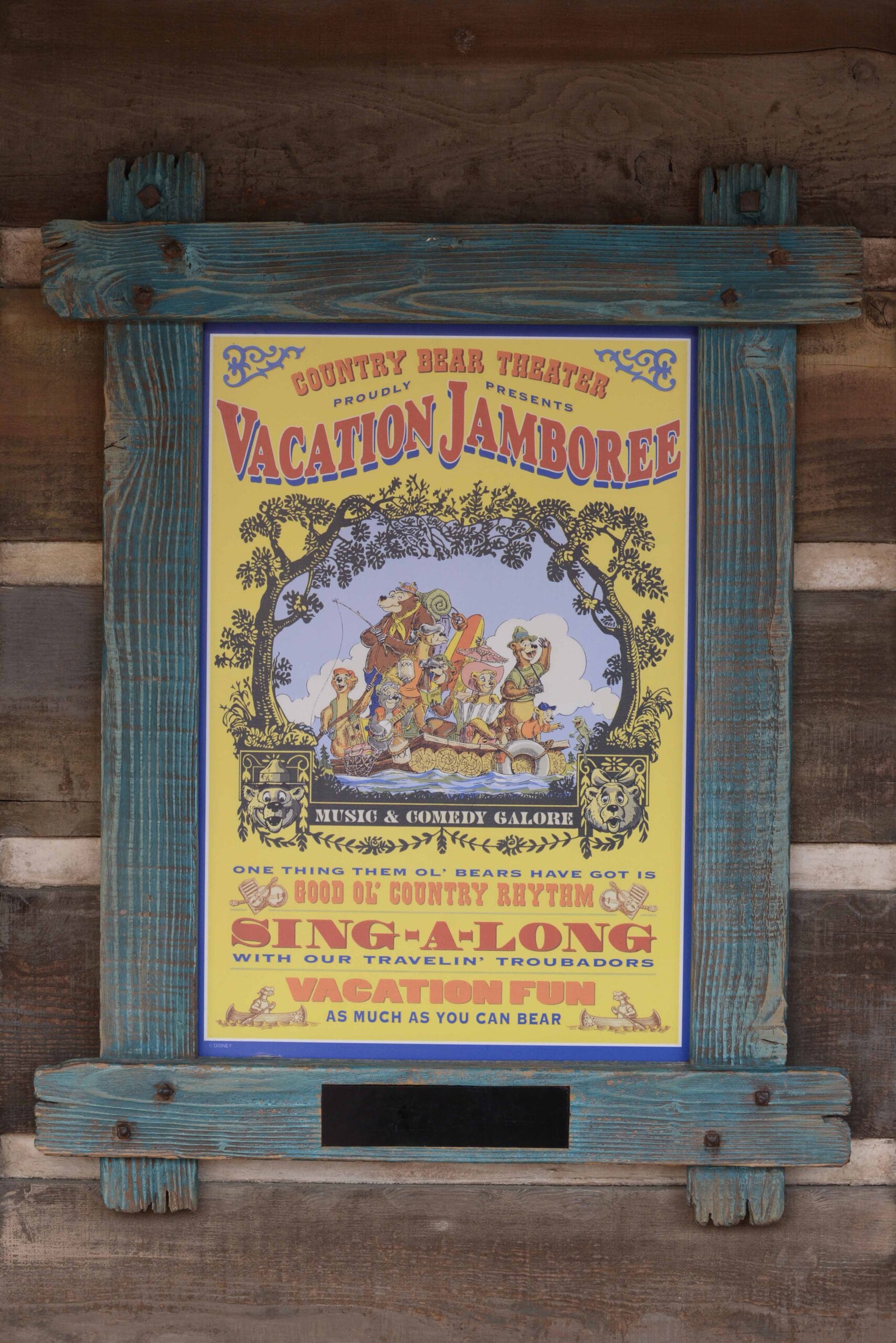 A colorful "Vacation Jamboree" poster in a rustic blue wooden frame, promoting a country bear show.