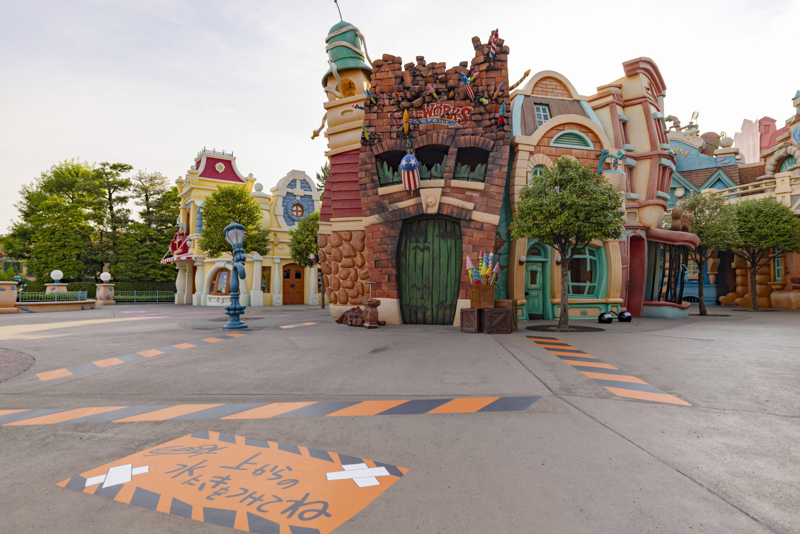 Cartoon-style buildings in a theme park with colorful facades and a sign with Japanese writing on the pavement.