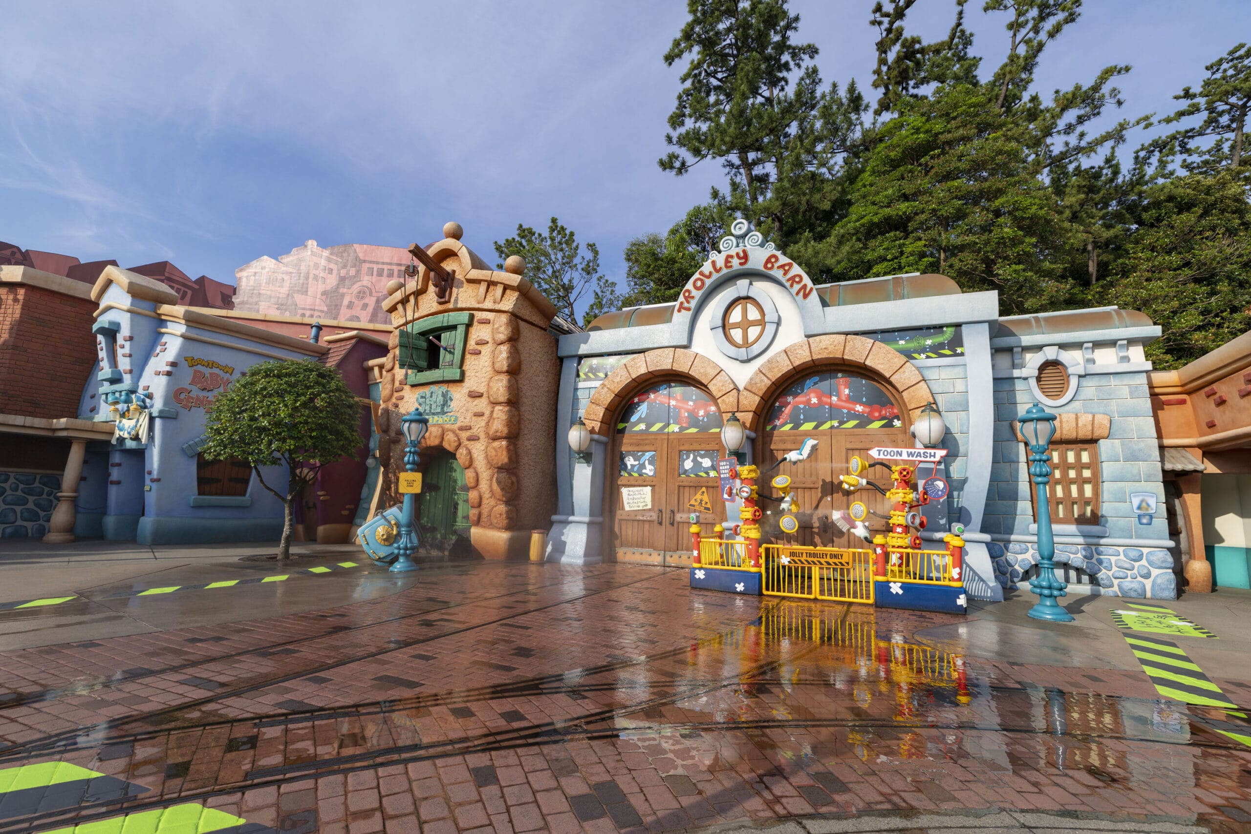A whimsical cartoon-style building with colorful decorations and a sign reading "Trolley Barn" in an amusement park.