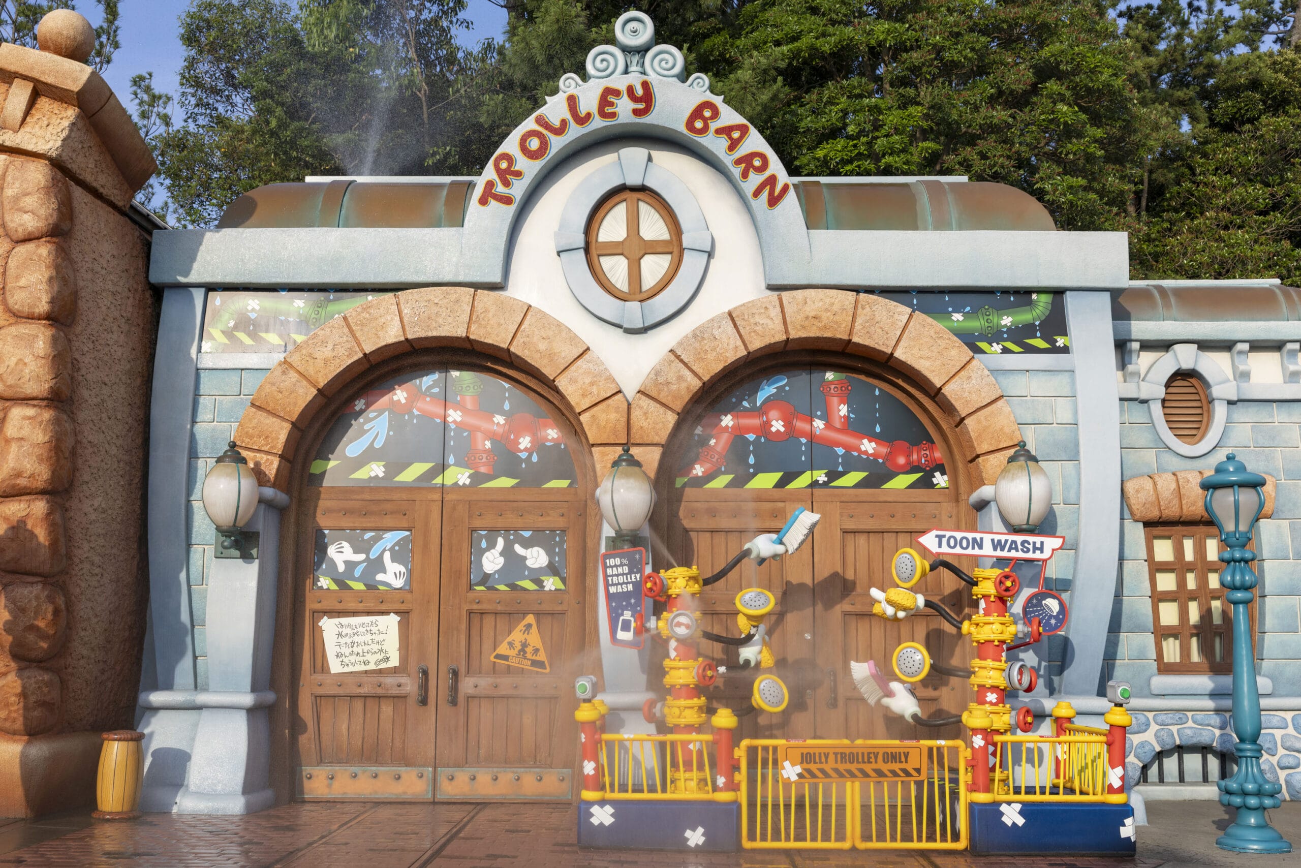 Colorful cartoon-style building with “Trolley Barn” sign and playful Toon Wash display in front, surrounded by greenery.