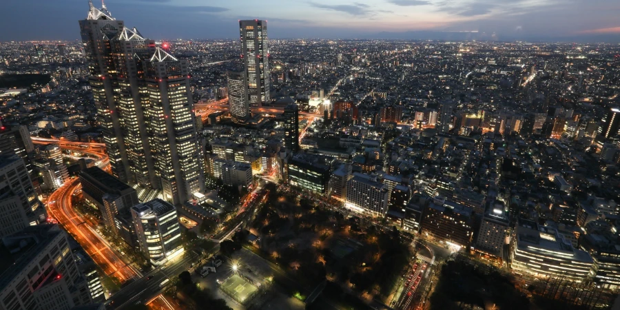 Aerial view of Tokyo at night, featuring the twin towers of the tokyo metropolitan government building