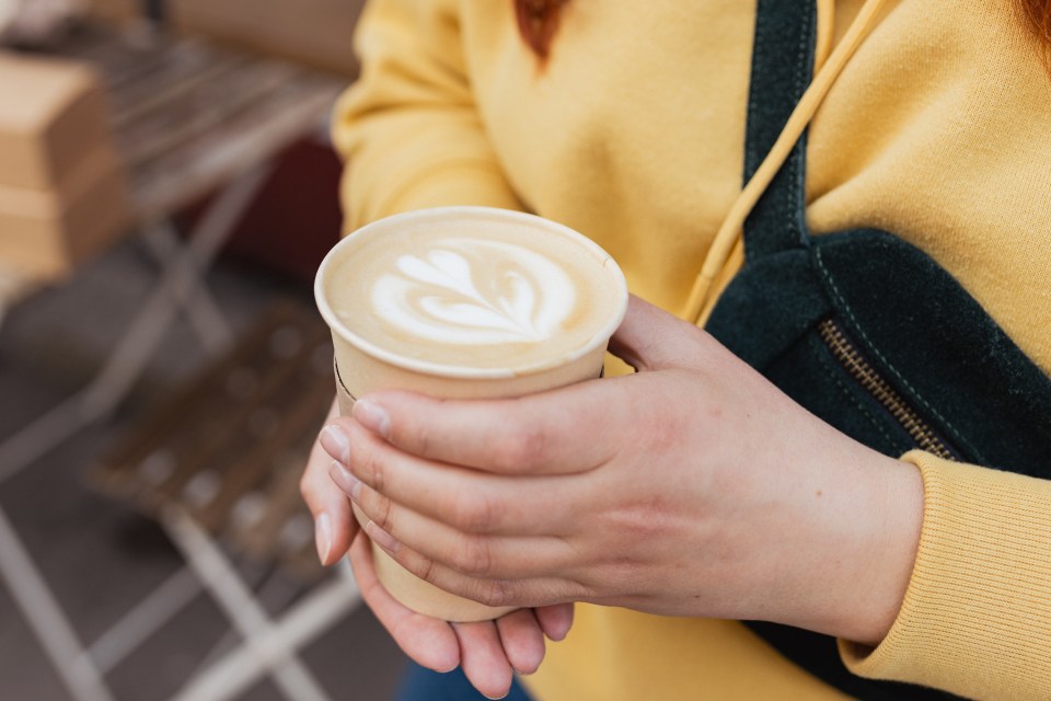 Woman's hands holding a paper cup of latte.