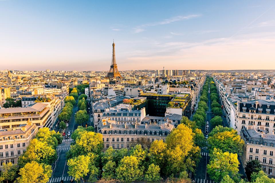 Elevated view of Paris cityscape with the Eiffel Tower in the distance, showcasing tree-lined streets and classic buildings