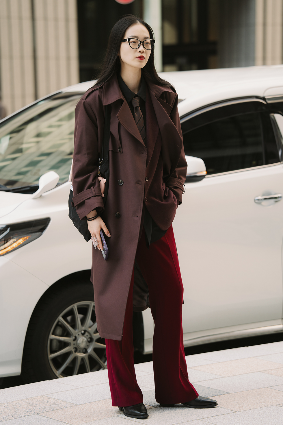 tokyo, japan march 22: a guest is seen wearing chanel glasses, dark red trench coat, jacket, tie, red trousers, black boots during rakuten tokyo fashion week a/w 2025 on march 22, 2025 in tokyo, japan. (photo by mila gruber/getty images)