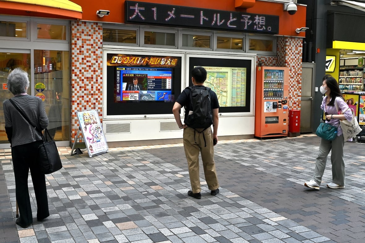People in central Tokyo watch a television broadcast about a tsunami warning for much of coastal Japan.