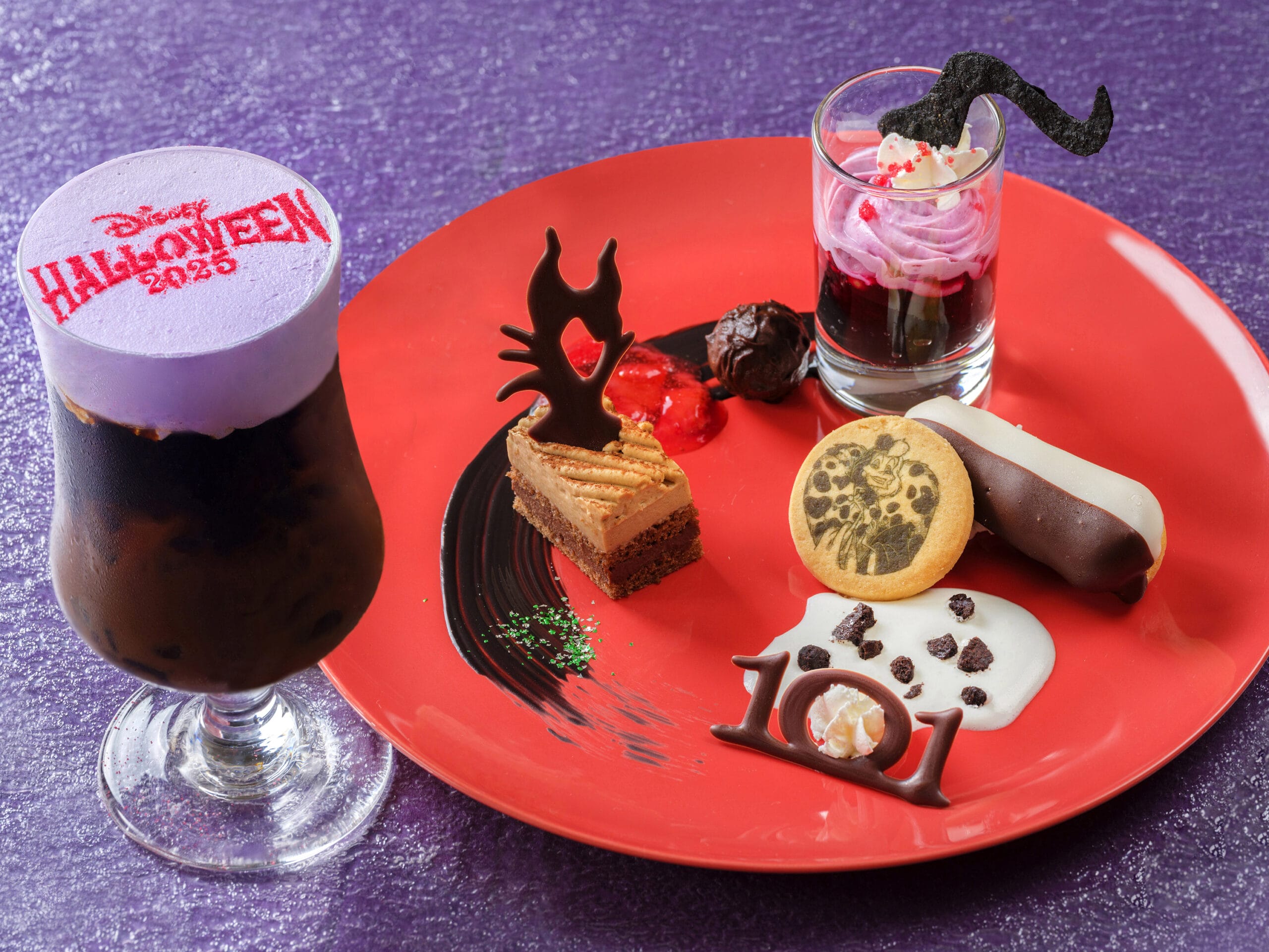 A Halloween-themed dessert plate and a purple drink at Tokyo Disney Resort, set on a festive purple surface.