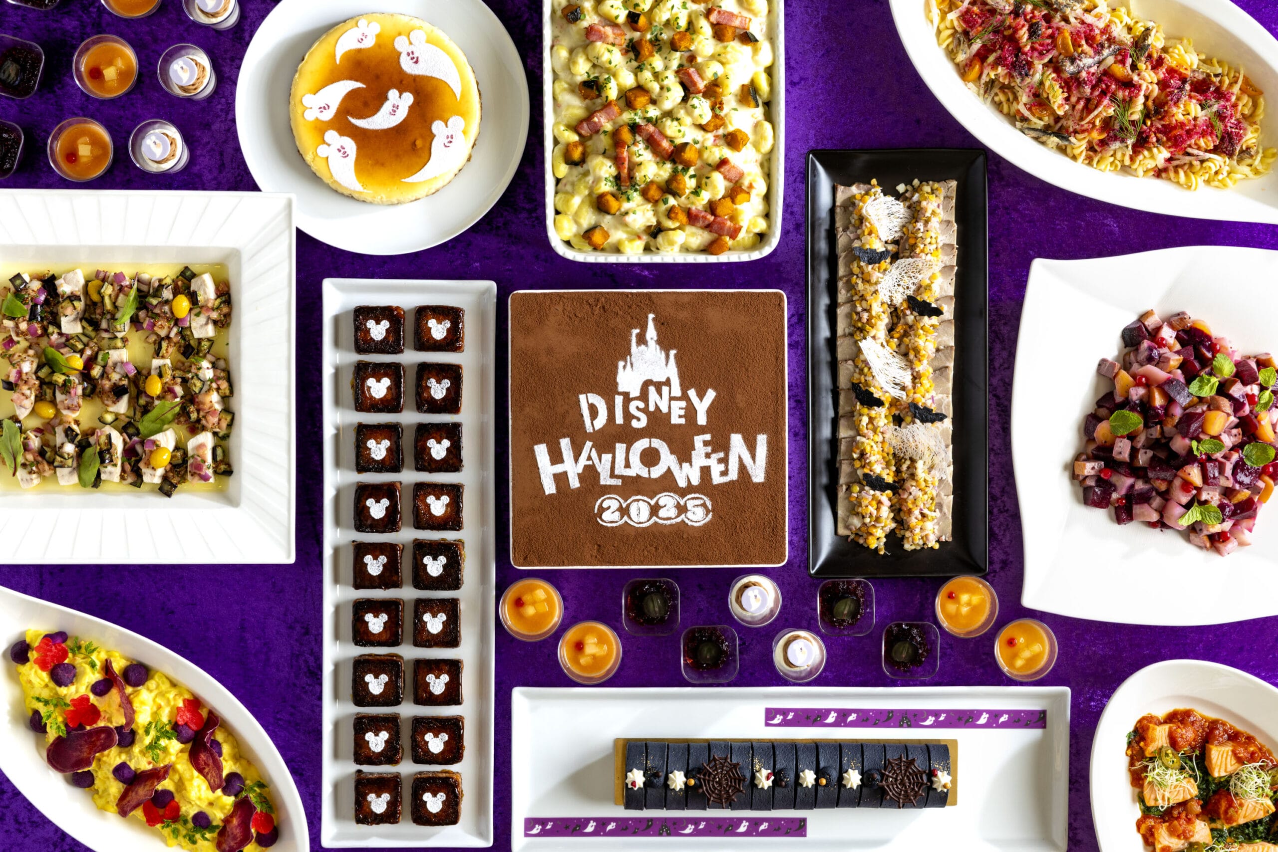 Assorted Halloween-themed Disney desserts at Tokyo Disney Resort on a purple table, with a festive cake centerpiece.