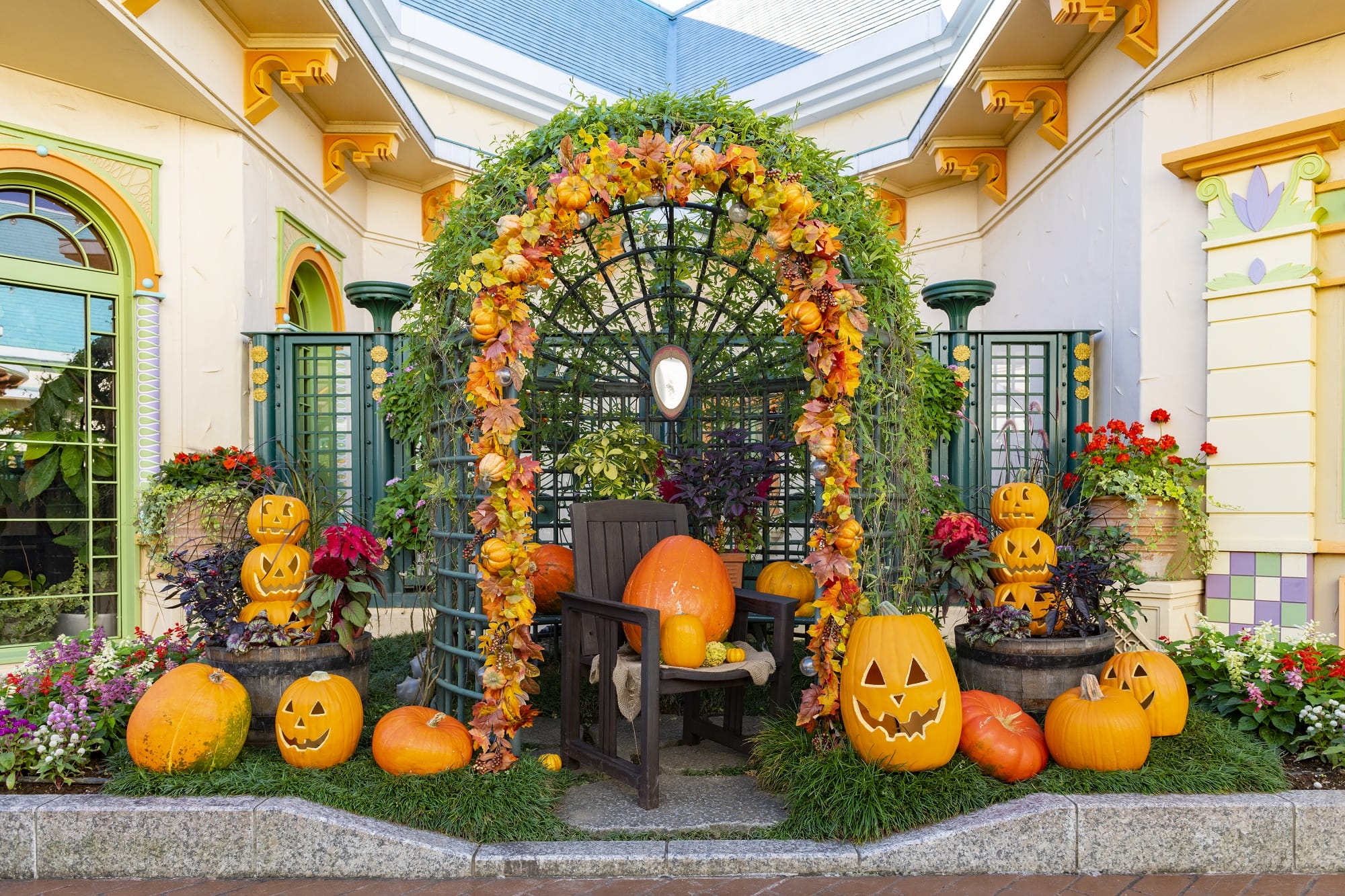 Garden arch at Tokyo Disney Resort adorned with autumn leaves, carved pumpkins, and flowers for Halloween.