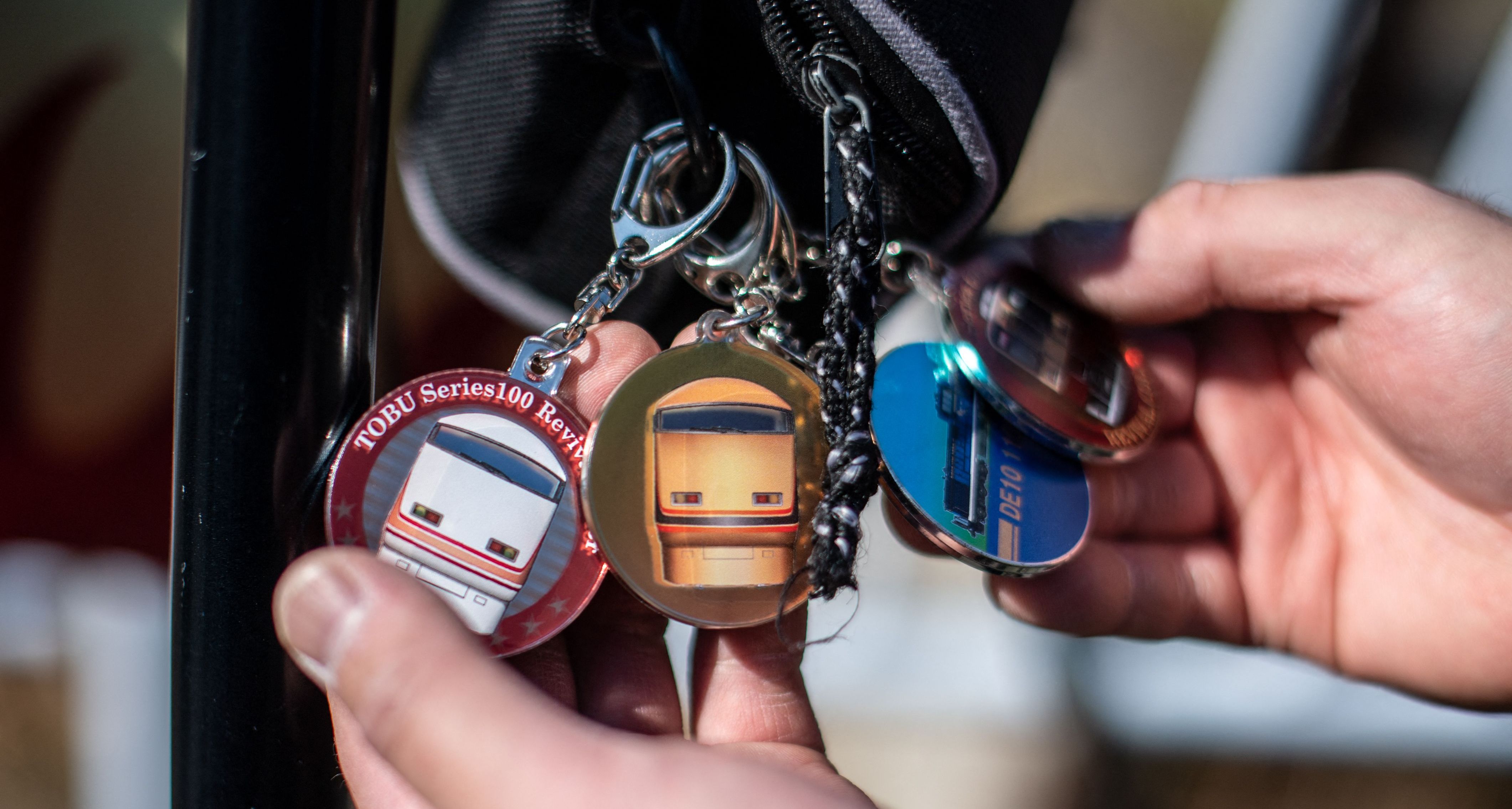 Person holding train-themed keychains.