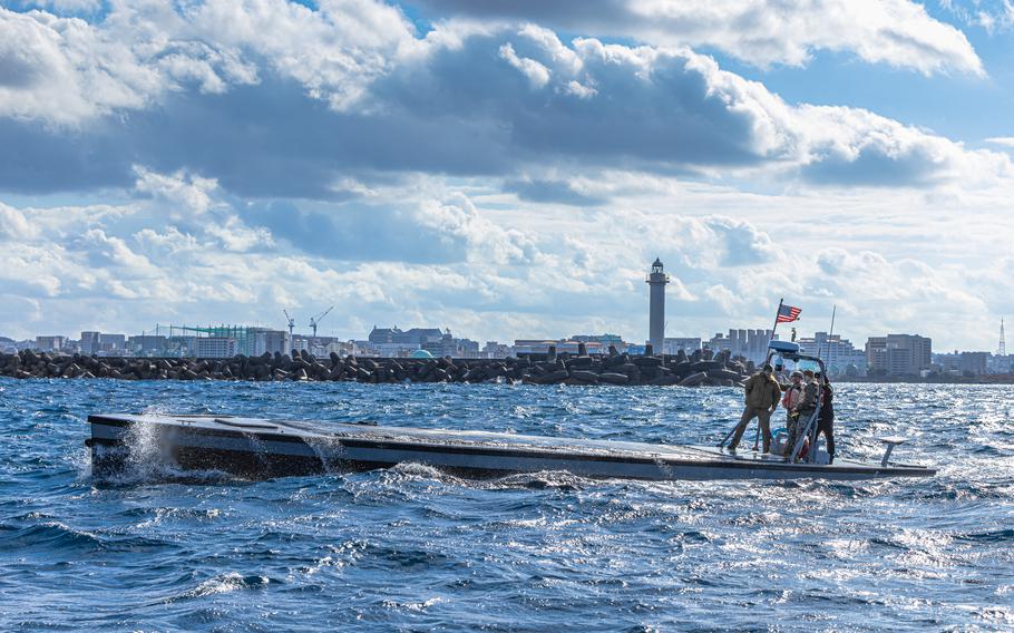 Marines operate a vessel with a low-profile deck that is nearly parallel with the water.