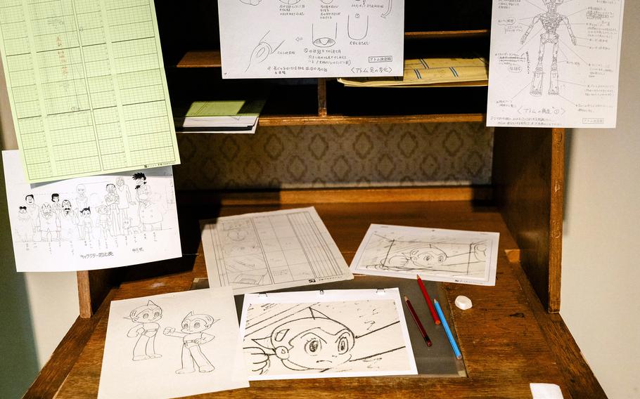 A wooden desk displays notes and drawings.