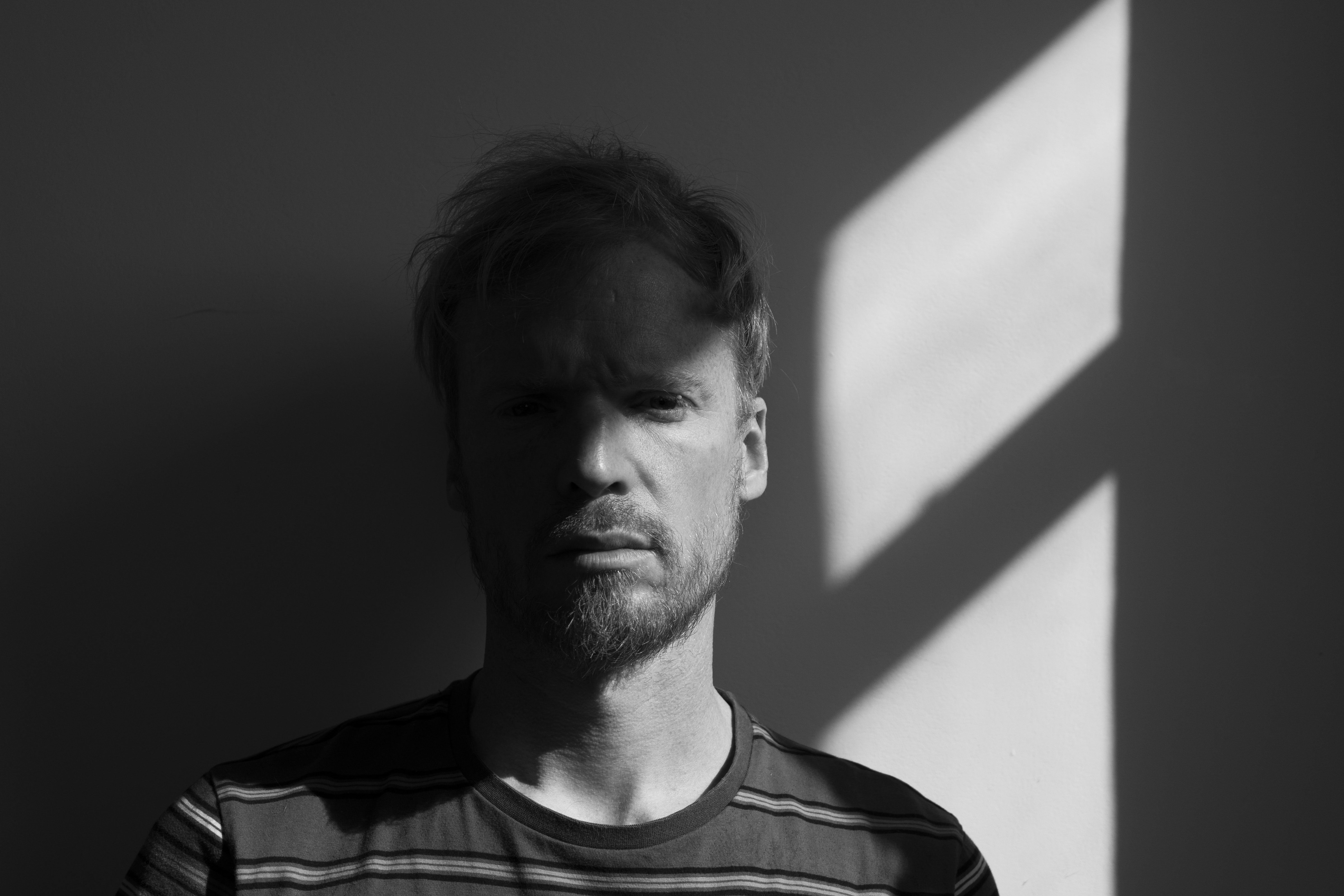 A man sitting next to a window in half sun