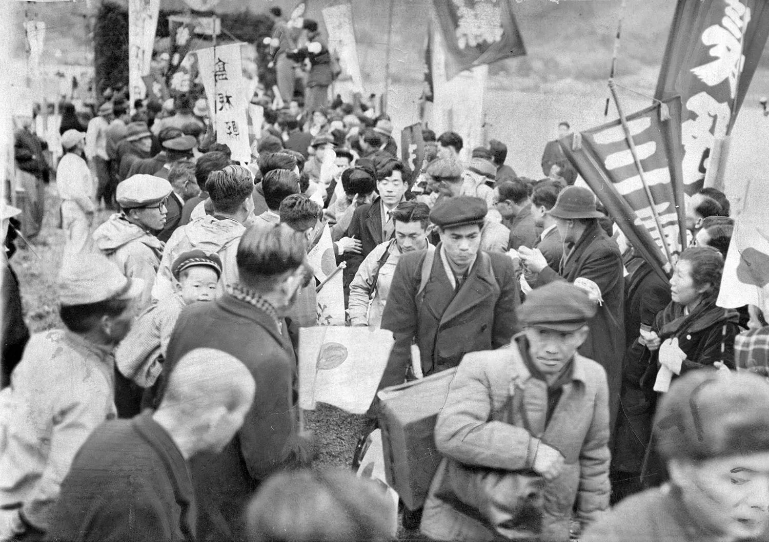 A crowd of people in coats and hats walk off a ship as they arrive in a port.