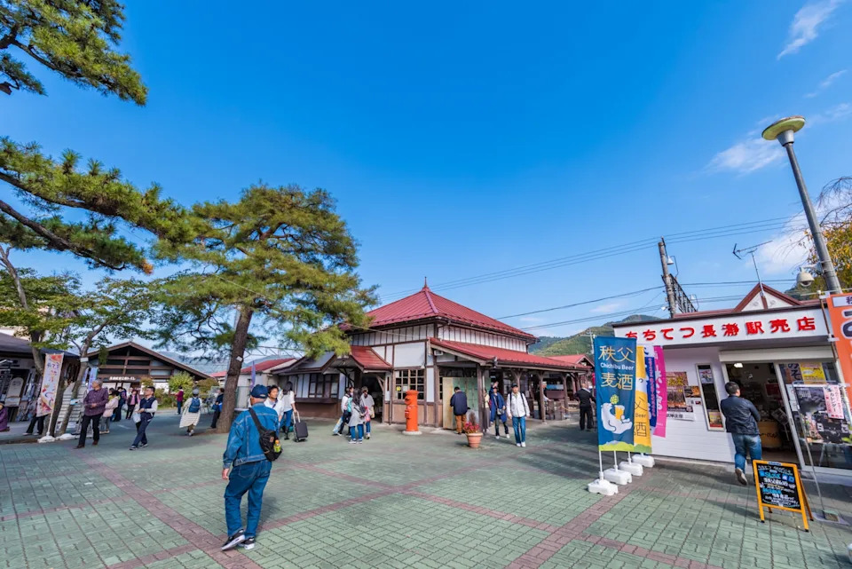 People walk around small shops, brick walk way under a blue sky.