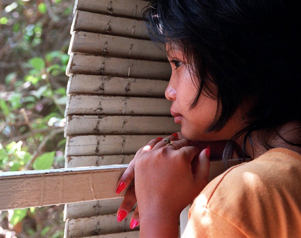 A 16-year-old girl peers out into the streets of Phnom Penh after being rescued from a brothel where she was forced to work. Photo: AFP