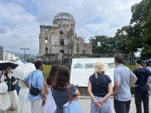 Students look at a sign outside of a exhibit/memorial in Hiroshima