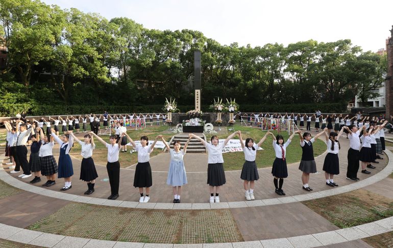High school students surround the monument marking the hypocentre of atomic bombing with a "human chain" to call for a peaceful world, in Nagasaki on August 9, 2024, to mark the 79th anniversary of the atomic bombing of the city. (Photo by JIJI Press / AFP) / Japan OUT / JAPAN OUT