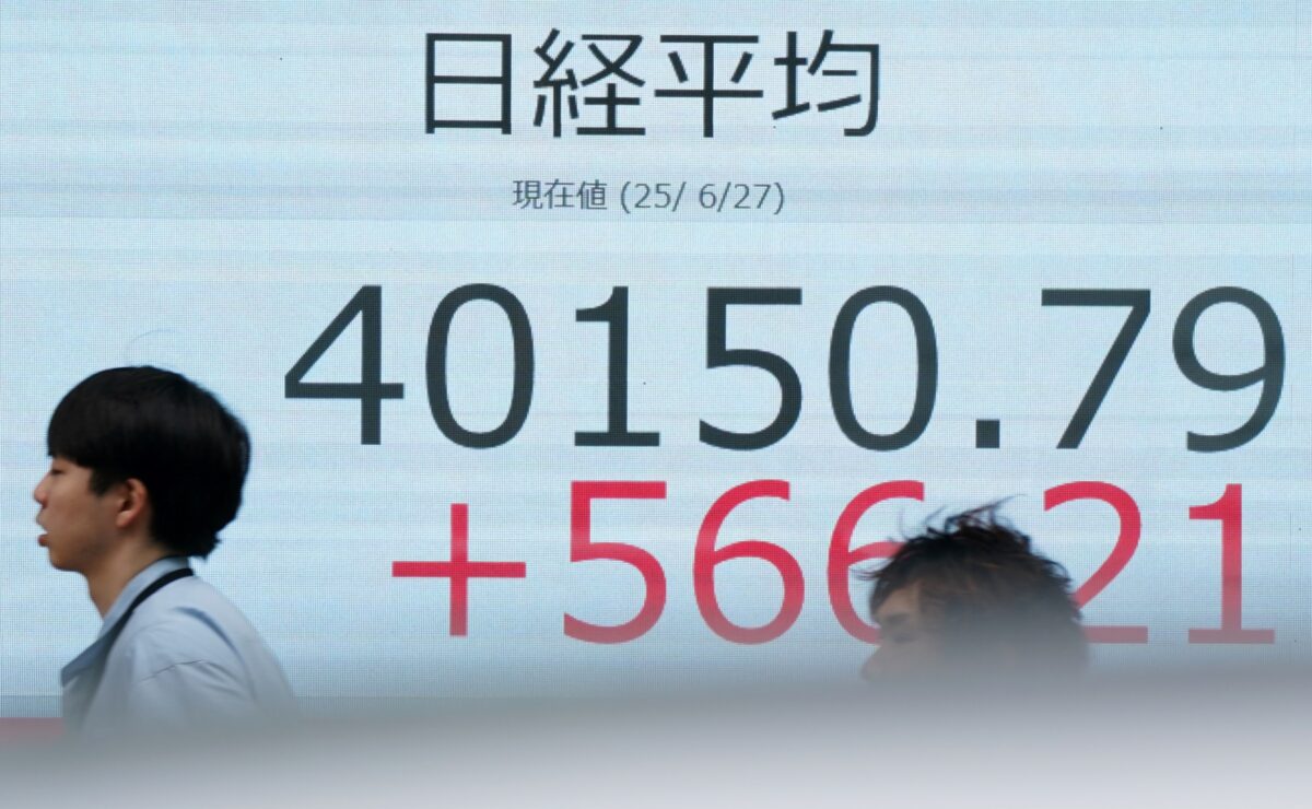 Pedestrians walk in front of an electronic quotation board displaying the Nikkei Stock Average closing price 