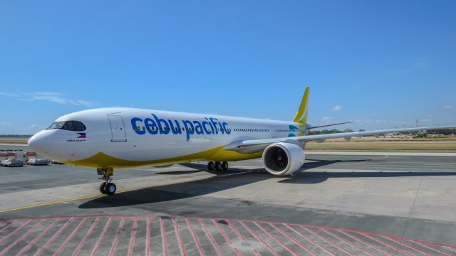 A Cebu Pacific airplane on the runway, showcasing the airline's logo and vibrant yellow and green color scheme under a clear blue sky.