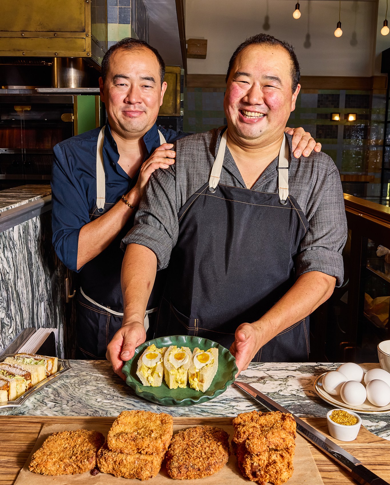 Two chefs posing in a kitchen.