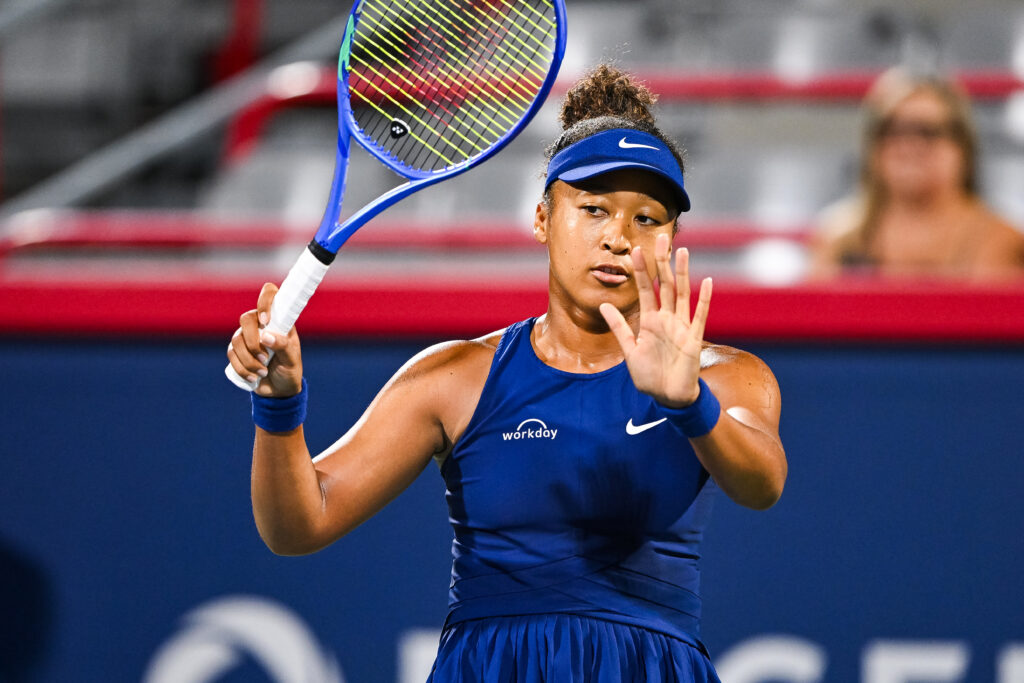 Naomi Osaka holds her hand up in apology