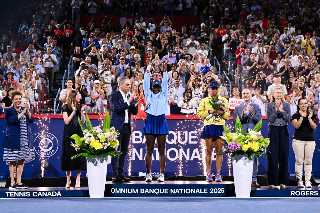 Victoria Mboko lifts her trophy next to a downbeat Naomi Osaka