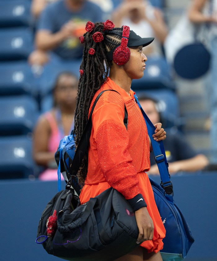 Naomi Osaka playing tennis in a red outfit